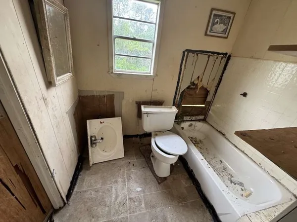 a white toilet sitting next to a bathroom sink and a mirror