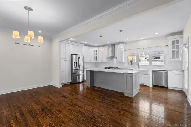 a open kitchen with white cabinets wooden floor and stainless steel appliances