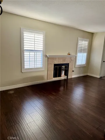 an empty room with wooden floor fireplace and windows