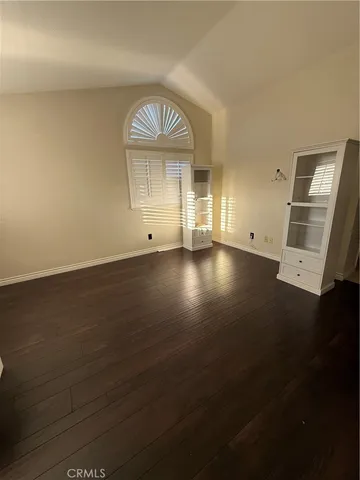 an empty room with wooden floor cabinet and windows