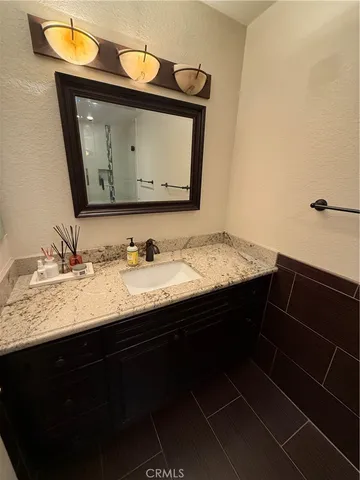 a bathroom with a granite countertop sink vanity and mirror