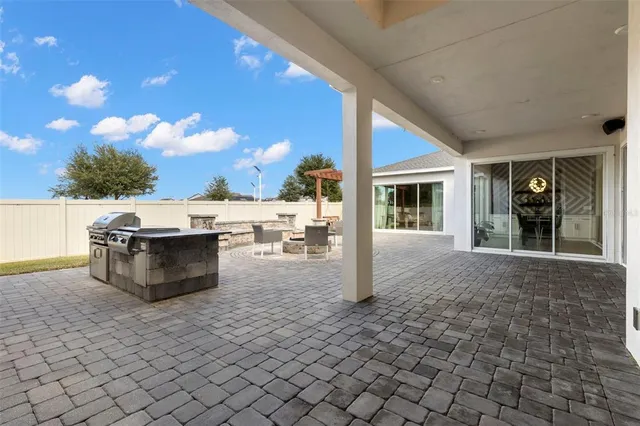 a view of a patio with dining table and chairs with a barbeque grill and a potted plant