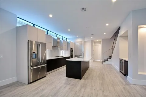 a large kitchen with a large counter top stainless steel appliances and wooden floor