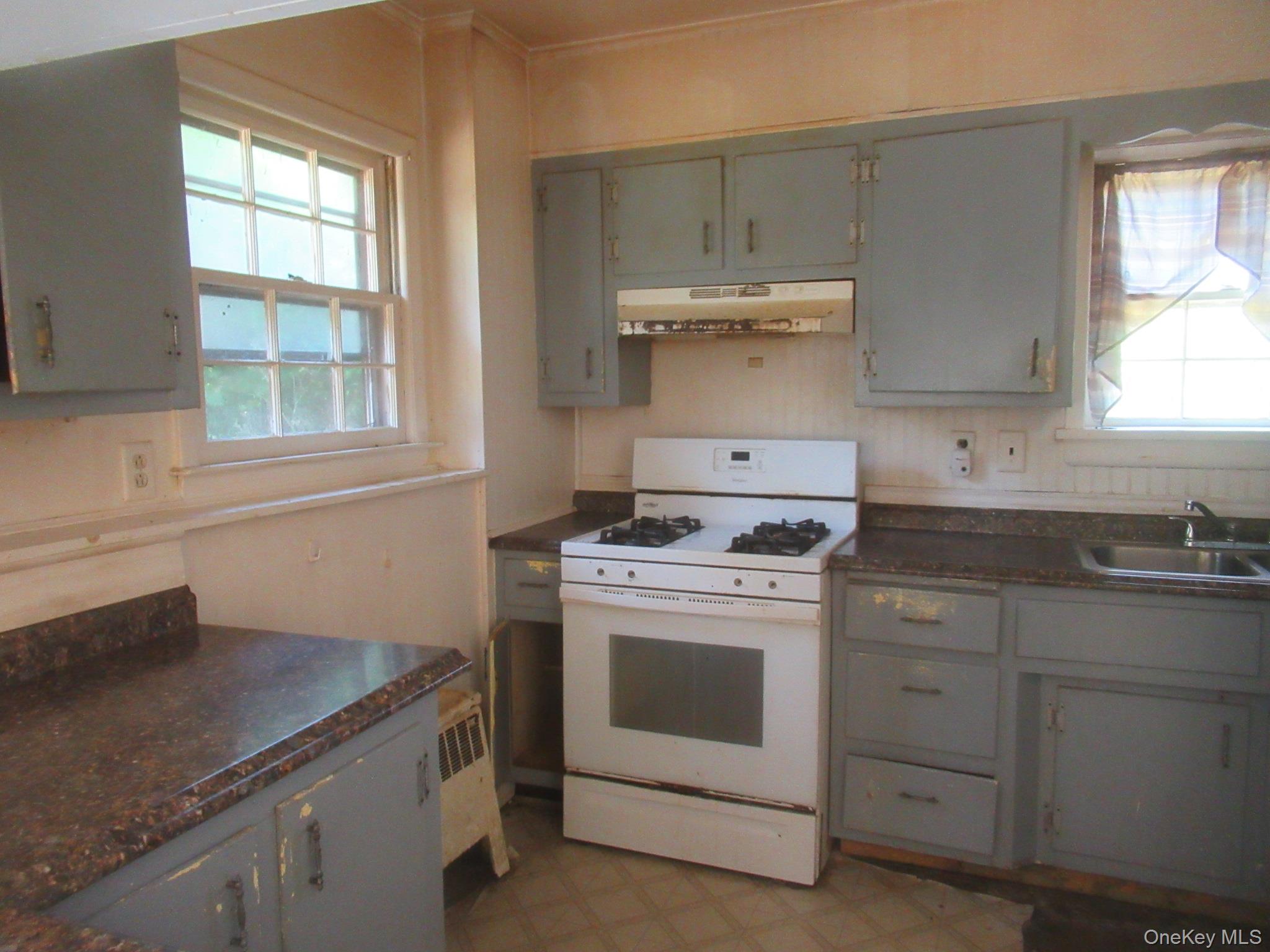 24 Edinburgh Road Middletown, NY 10941 - Photo 16 of 17 Kitchen featuring white gas range, under cabinet range hood, dark countertops, light floors, and gray cabinetry