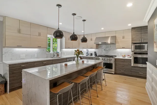 a kitchen with stainless steel appliances granite countertop a sink a stove and a wooden floors