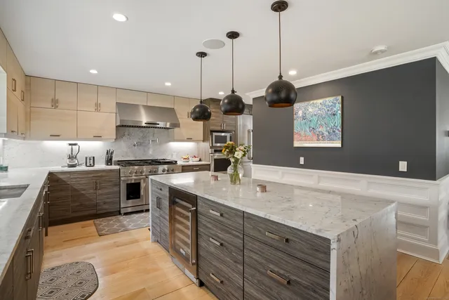 a kitchen with stainless steel appliances kitchen island granite countertop a sink a stove and a wooden floor