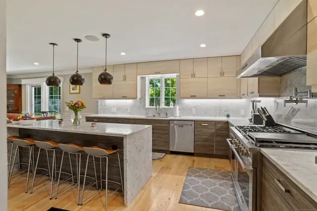 a kitchen with kitchen island granite countertop a stove a sink a oven and wooden cabinets