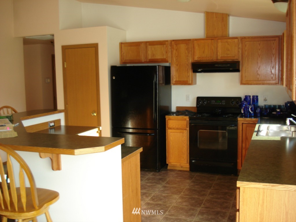 7325 187th Court Southwest Rochester, WA 98579 - Photo 5 of 9 a kitchen with granite countertop a refrigerator a stove and a sink