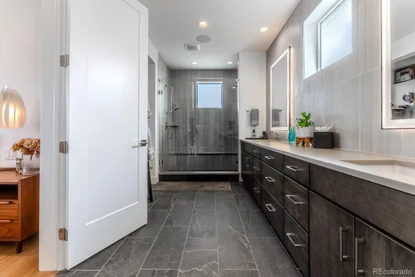 a bathroom with a double vanity sink a large mirror a shower and a bathtub