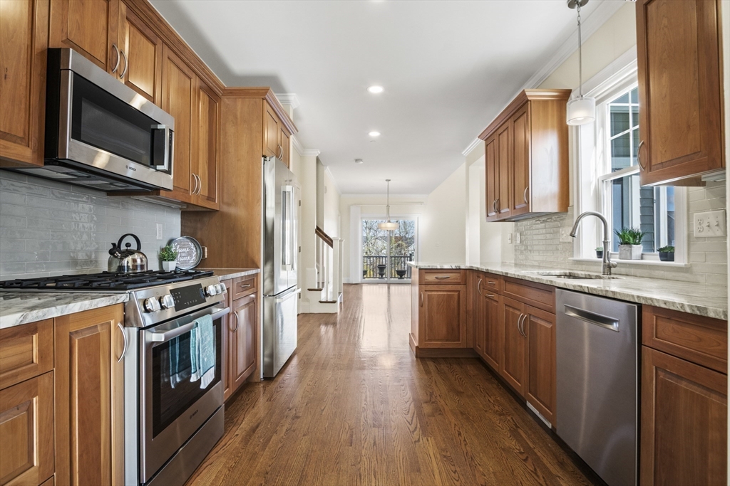 16 Winning Farm Road, Unit 16 Woburn, MA 01801 - Photo 11 of 42 a kitchen with stainless steel appliances granite countertop hardwood floor sink stove and wooden cabinets