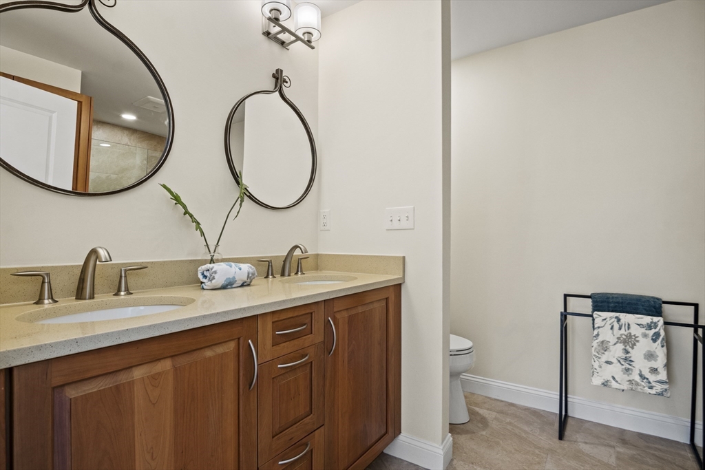 16 Winning Farm Road, Unit 16 Woburn, MA 01801 - Photo 24 of 42 a bathroom with a granite countertop toilet a sink and a mirror