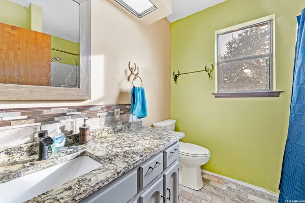 a bathroom with a granite countertop sink and a mirror