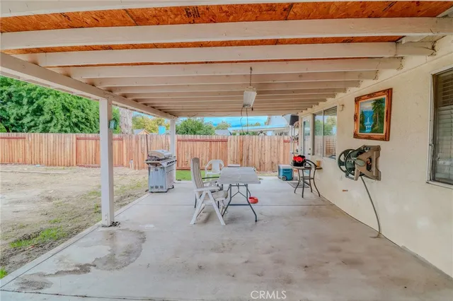 a view of a patio with table and chairs under an umbrella with a small yard