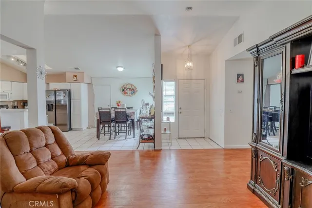 a living room with furniture a flat screen tv and a refrigerator
