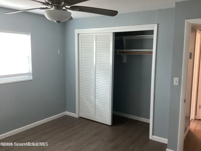 an empty room with wooden floor closet and windows
