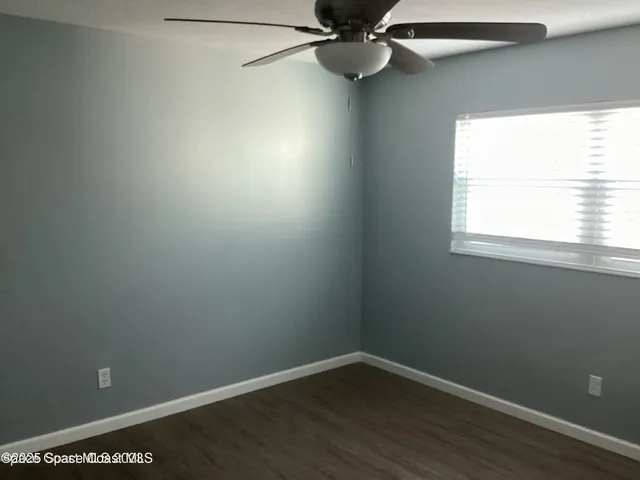 an empty room with a window and a fan