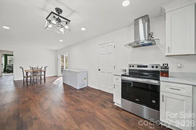 a kitchen with stainless steel appliances a stove a sink and white cabinets with wooden floor