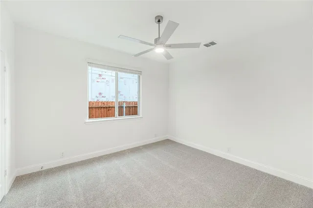 an empty room with a window and ceiling fan