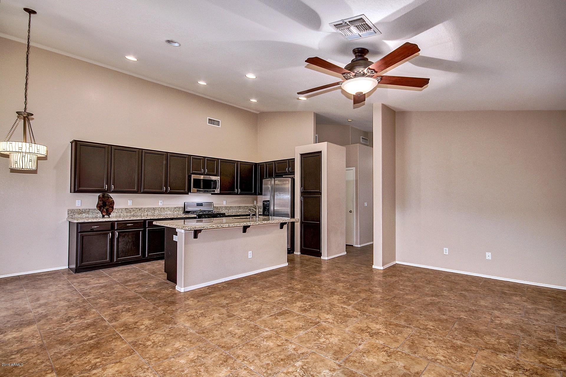 16056 South 18th Avenue Phoenix, AZ 85045 - Photo 11 of 37 a kitchen with stainless steel appliances kitchen island granite countertop a refrigerator and a stove top oven