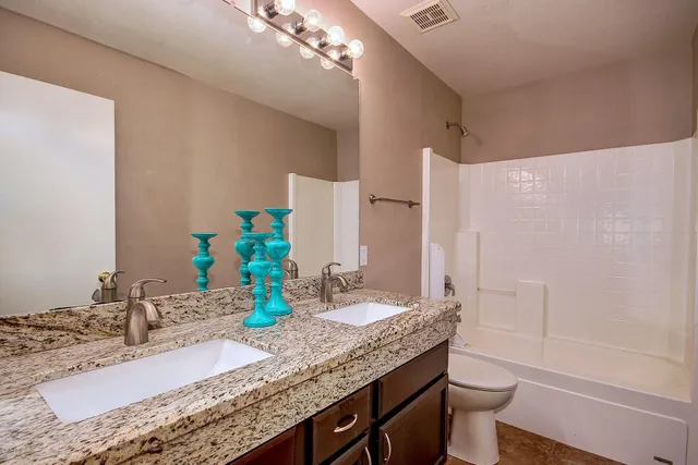 a bathroom with a granite countertop bathtub sink vanity mirror and toilet