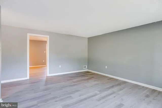 a view of an empty room with wooden floor and closet