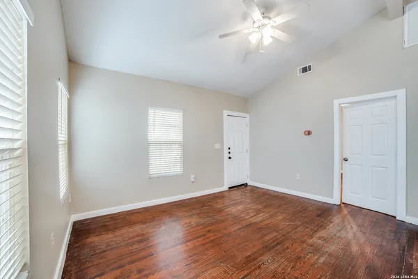 a view of an empty room with window and wooden floor