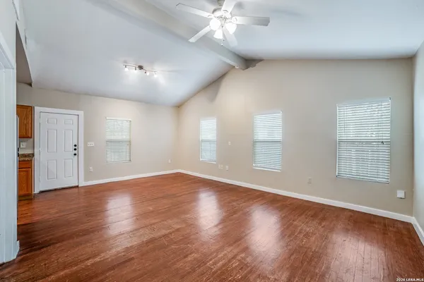 a view of an empty room with wooden floor and a window