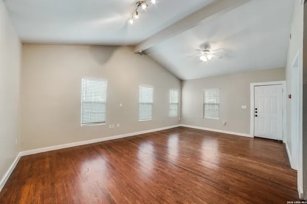 an empty room with wooden floor and windows