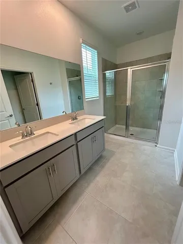 a bathroom with a double vanity sink mirror and shower
