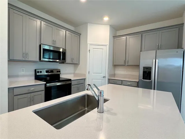 a kitchen with granite countertop a refrigerator and a stove top oven