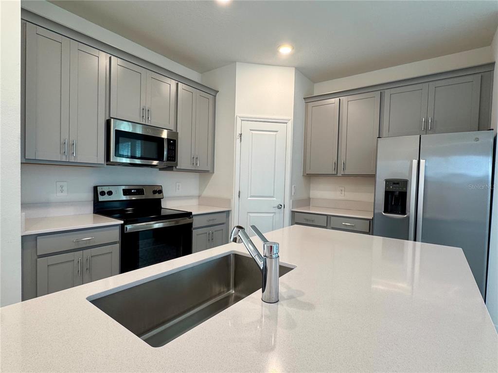 6473 Pine Warbler Way St. Cloud, FL 34771 - Photo 5 of 27 a kitchen with granite countertop a refrigerator and a stove top oven