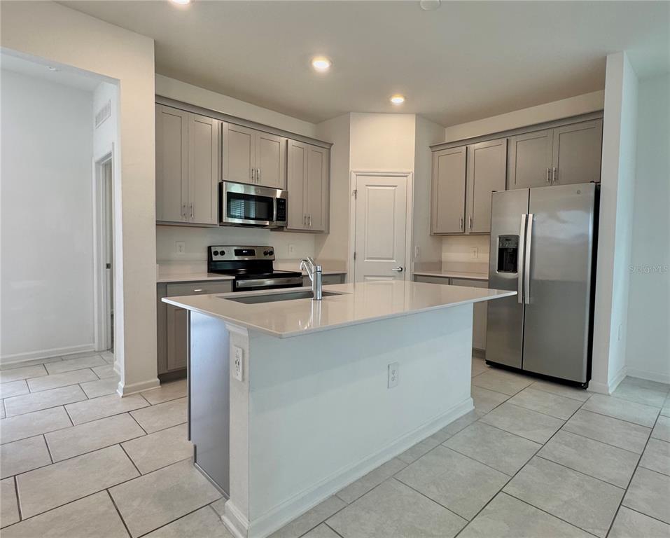 6473 Pine Warbler Way St. Cloud, FL 34771 - Photo 6 of 27 a kitchen with stainless steel appliances a refrigerator sink and microwave