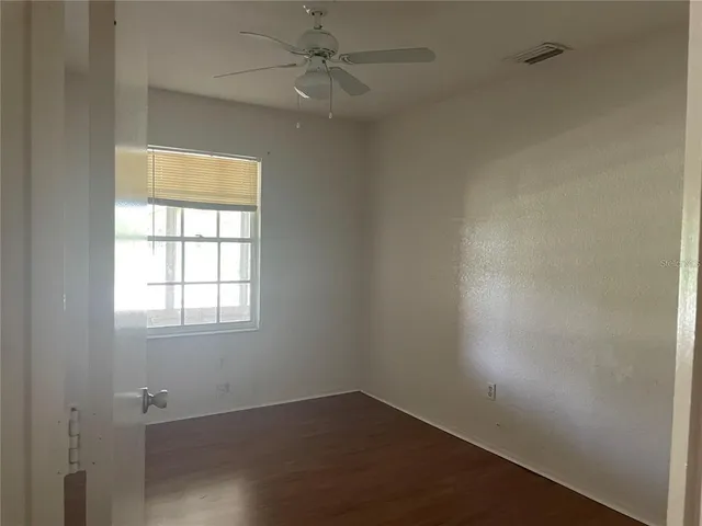 an empty room with a window and a fan