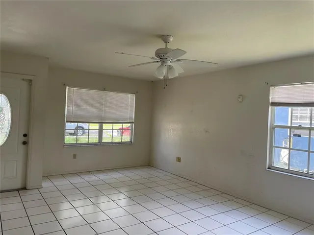 an empty room with windows and fan