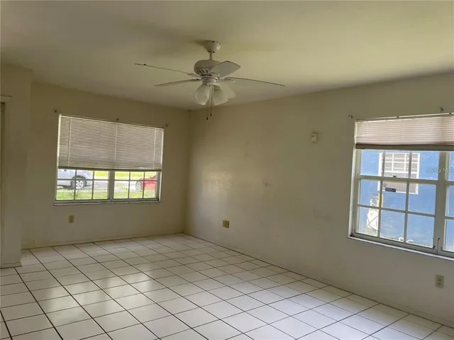an empty room with windows and fan