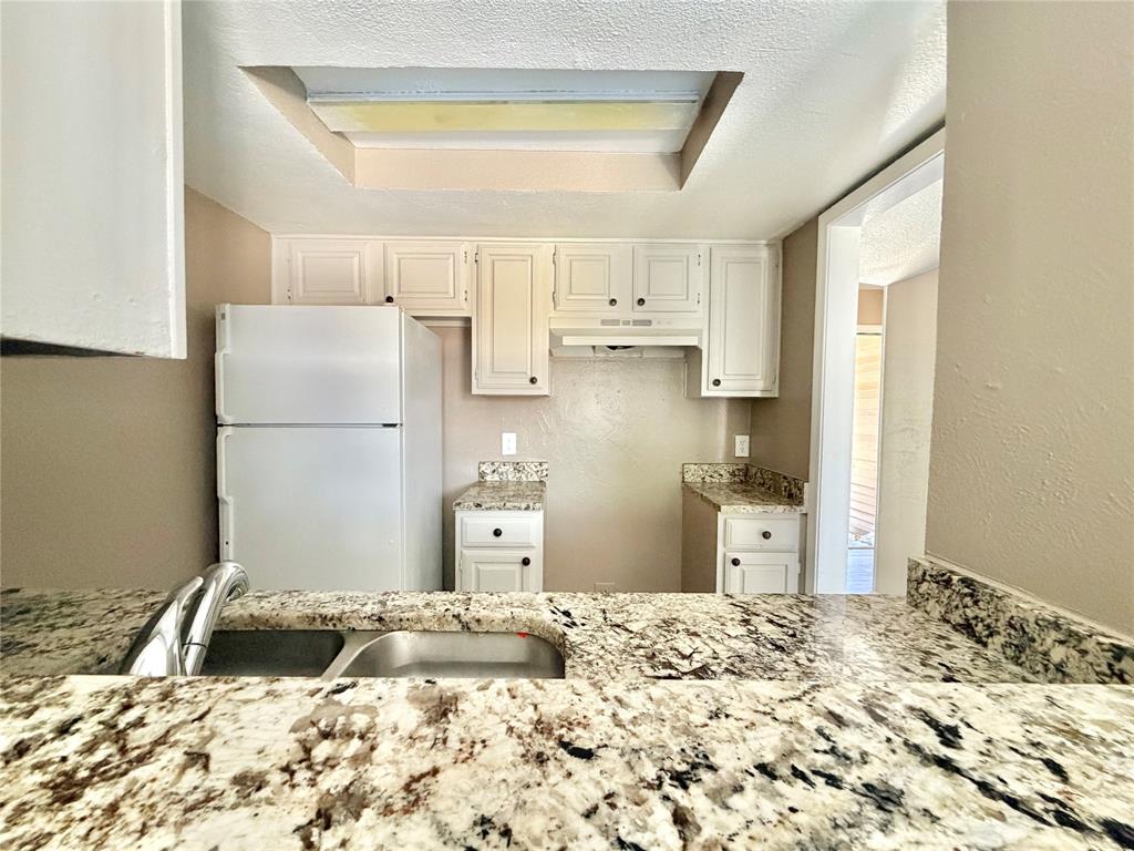 8001 Rothington Road, Unit 33 Dallas, TX 75227 - Photo 5 of 15 Kitchen featuring white cabinetry, granite-style countertops, an undermount double-basin stainless steel sink with a chrome faucet, and a built-in overhead light fixture