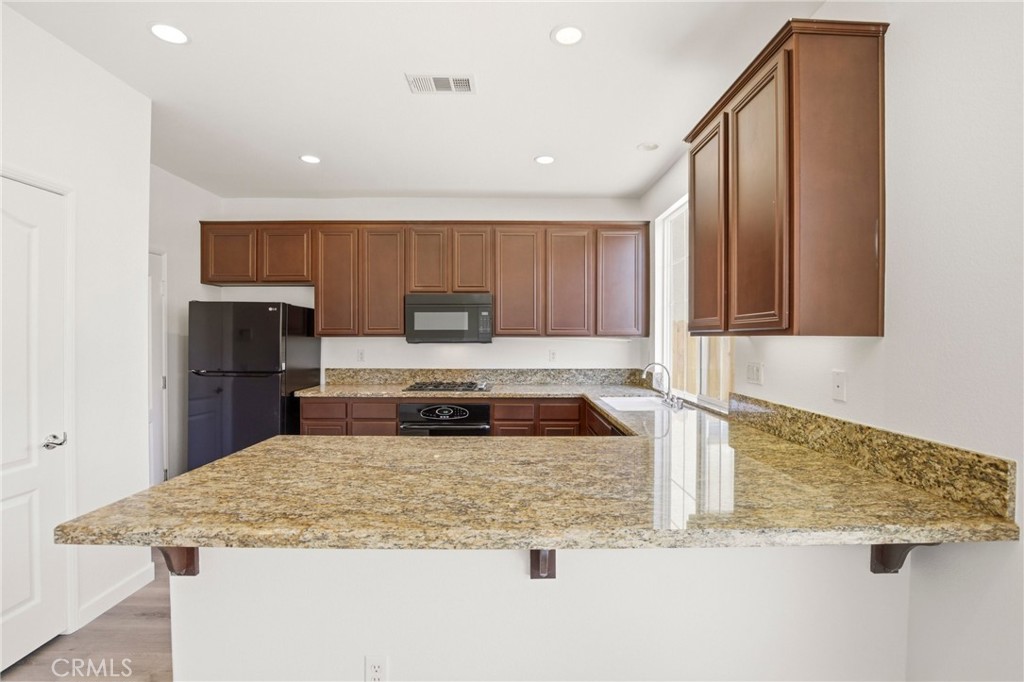 31598-31598 Six Rivers Court Temecula, CA 92592 - Photo 16 of 43 a kitchen with kitchen island granite countertop a sink a stove and a refrigerator
