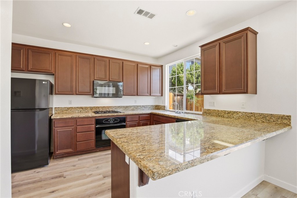 31598-31598 Six Rivers Court Temecula, CA 92592 - Photo 17 of 43 a kitchen with granite countertop wooden cabinets a refrigerator stove top oven and sink