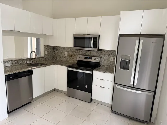 a kitchen with stainless steel appliances granite countertop white cabinets a refrigerator and a stove