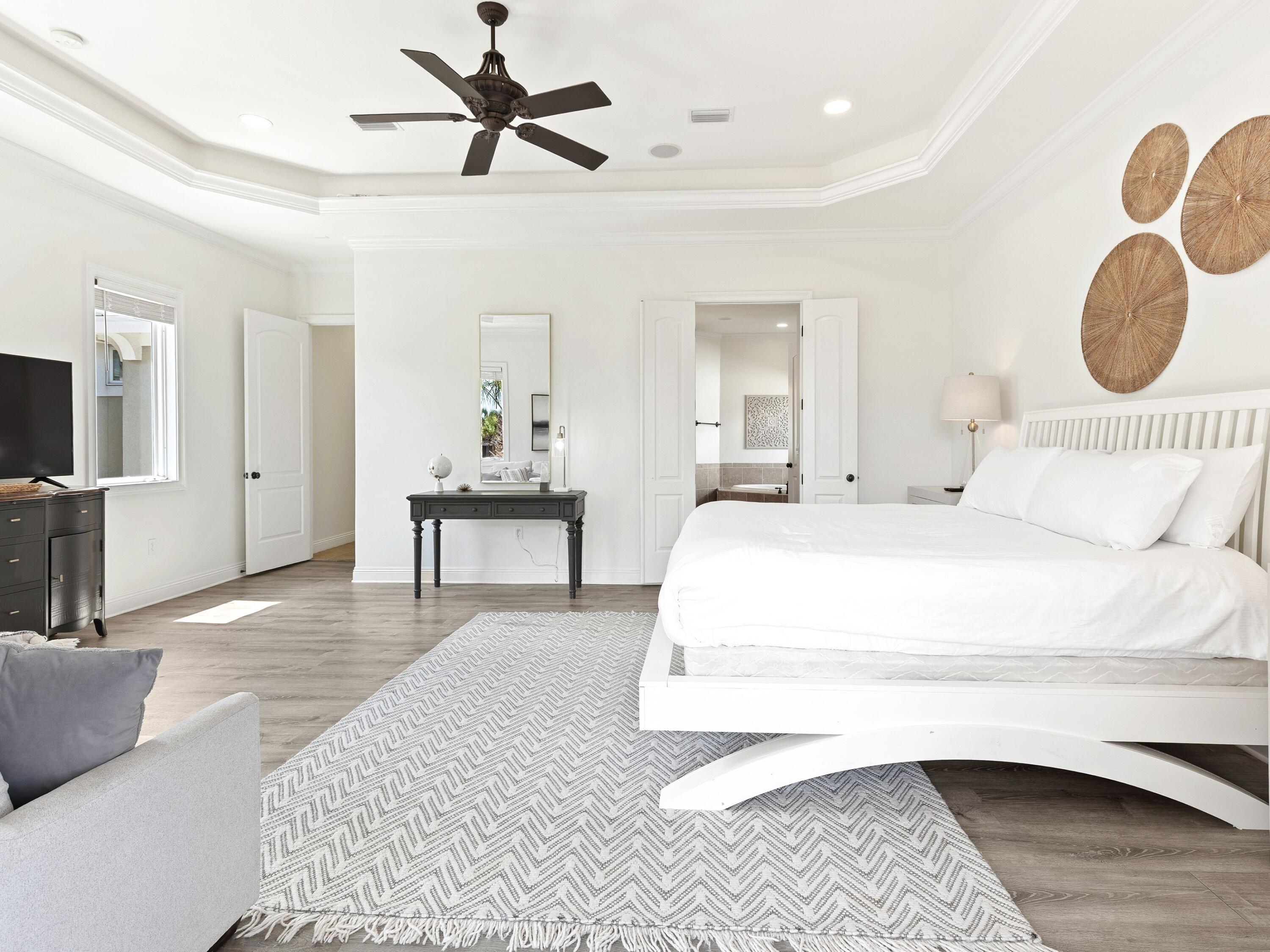 52 Tranquility Lane Destin, FL 32541 - Photo 41 of 65 a spacious bedroom with a bed a mirror on dresser and a chandelier