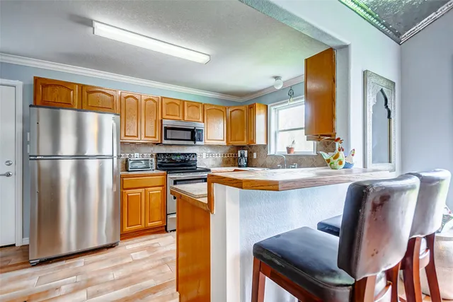 a kitchen with stainless steel appliances granite countertop a refrigerator a stove a sink dishwasher a dining table and chairs with wooden floor