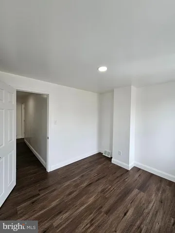 a view of an empty room with wooden floor and closet