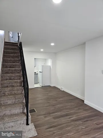 a view of empty room with stairs and wooden floor