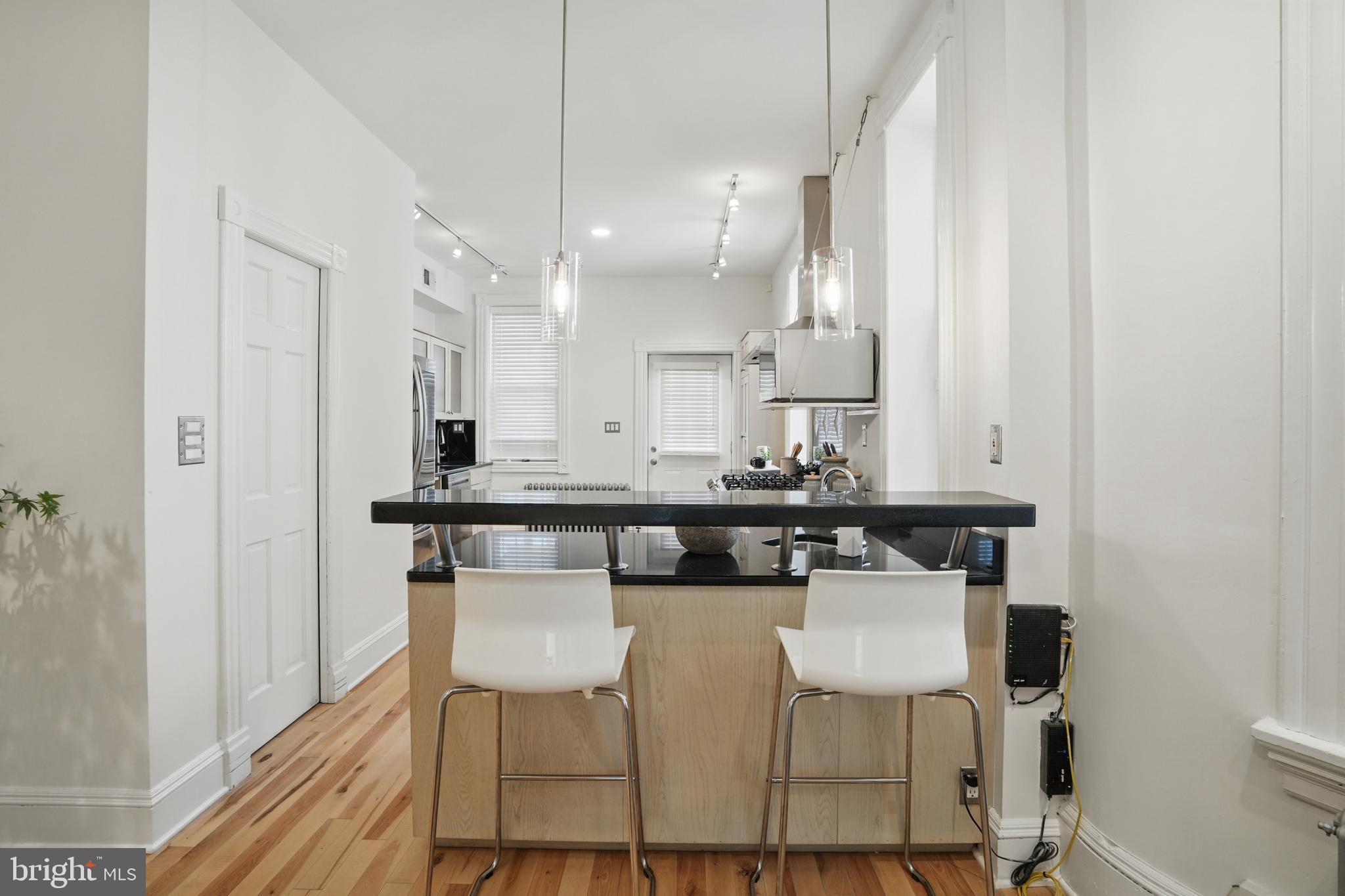 136 R Street Northeast Washington, DC 20002 - Photo 11 of 36 a kitchen with stainless steel appliances kitchen island granite countertop a table chairs a sink and white cabinets