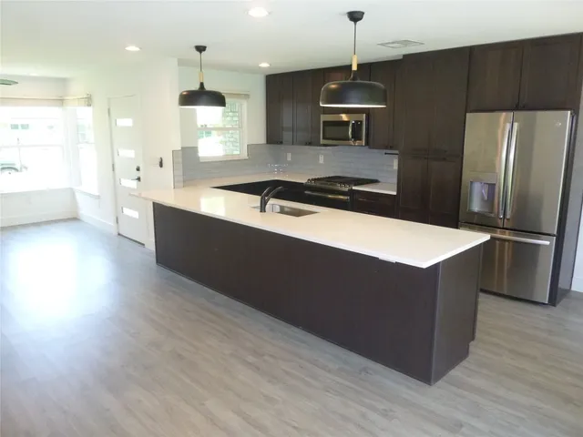 a kitchen with stainless steel appliances granite countertop a sink a stove a refrigerator and a oven