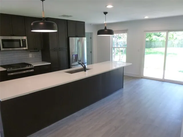 a kitchen with stainless steel appliances a refrigerator sink and wooden floor