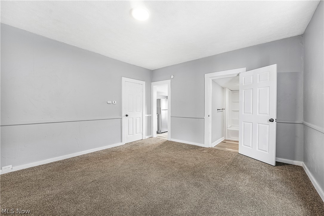 885 Wales Road Northeast Massillon, OH 44646 - Photo 25 of 34 Spacious room featuring neutral carpeting, light gray walls with chair rail detailing, white trim, and two white panel doors