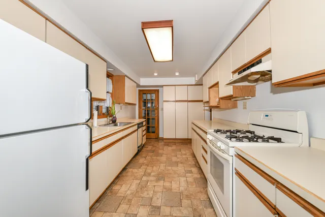 a kitchen with stainless steel appliances granite countertop a refrigerator a stove a sink dishwasher and white countertops with wooden floor