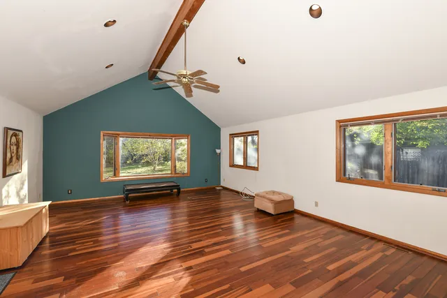 a view of an empty room with window and wooden floor