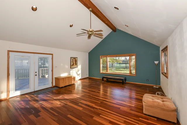 a view of an empty room with window and wooden floor